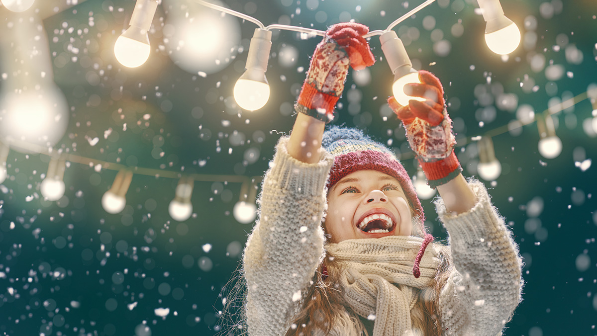 stay sanitized this holidays season - girl smiling enjoying the snow and holiday lights